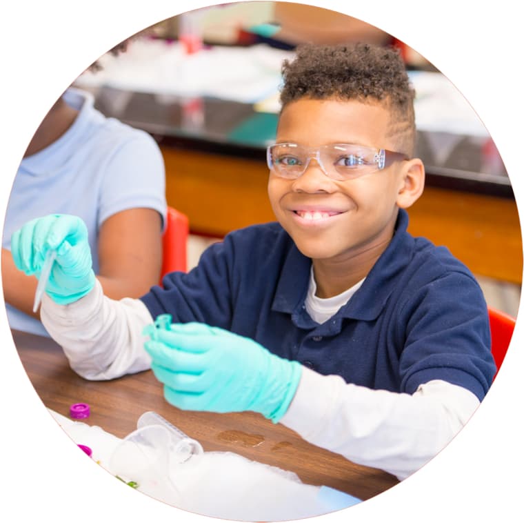 (image) A young scientists looks pleased in the classroom